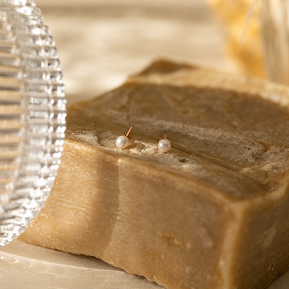 Two pearl earrings on a bar of soap with a blurred background