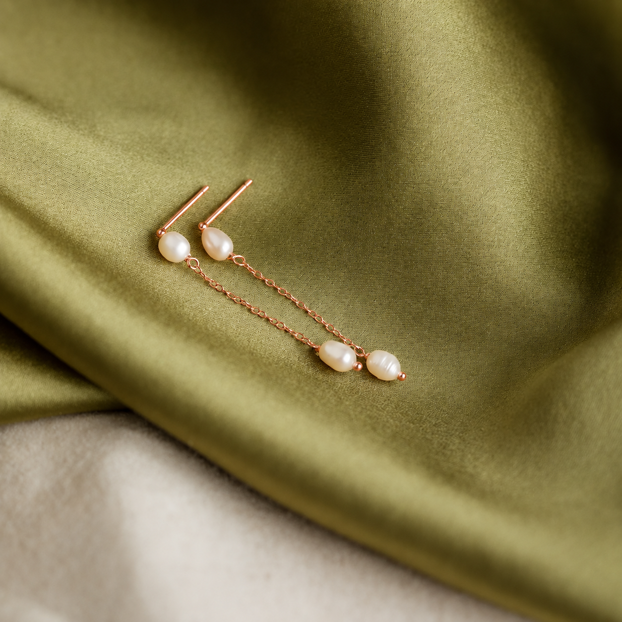 Pearl earrings on a green fabric background