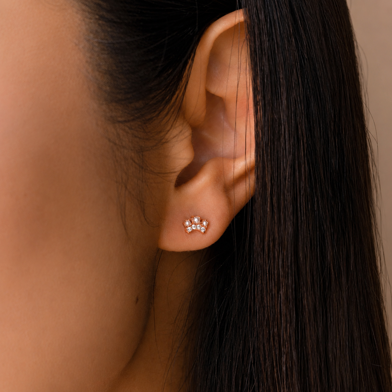 Close-up of an ear wearing a floral earring with dark hair and skin background