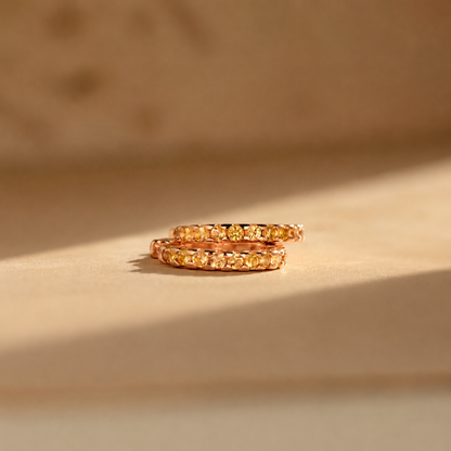 Two gold rings with embedded stones on a beige background