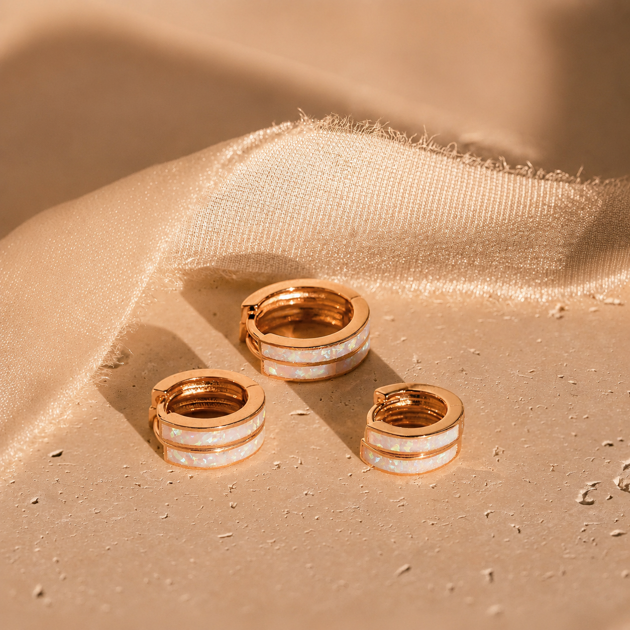 Gold hoop earrings on a textured beige surface