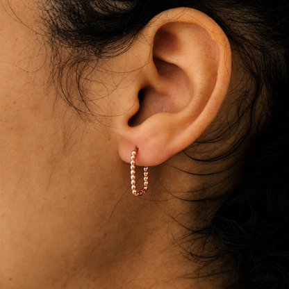 Close-up of an ear wearing a rose gold hoop earring.