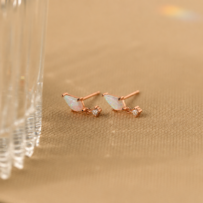 Rose gold earrings with opal stones on a beige background
