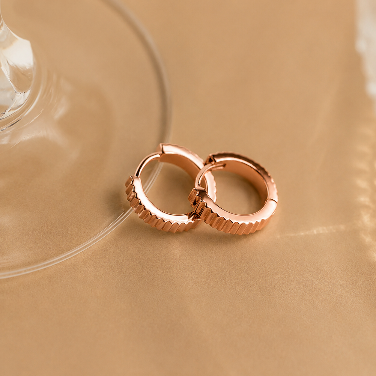 Rose gold hoop earrings on a beige background