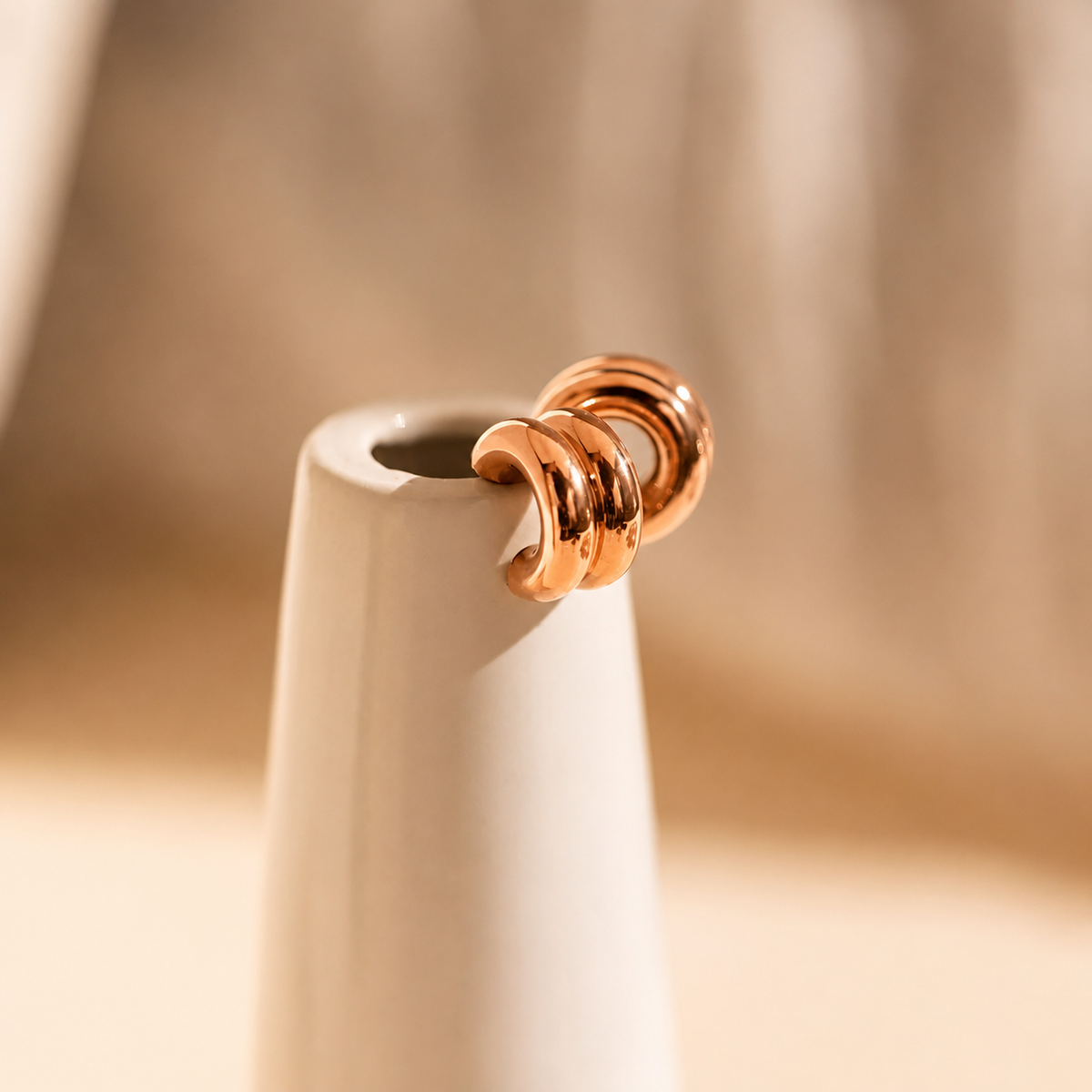 Rose gold earring on a beige background