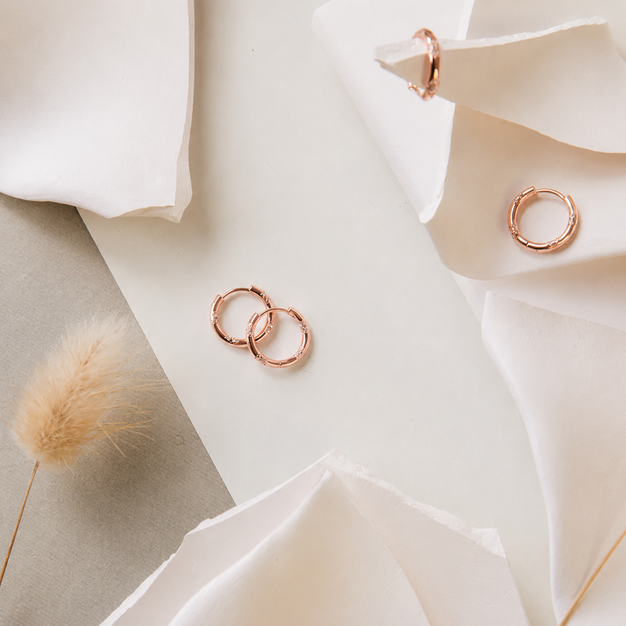 Rose gold hoop earrings on white fabric with a soft background