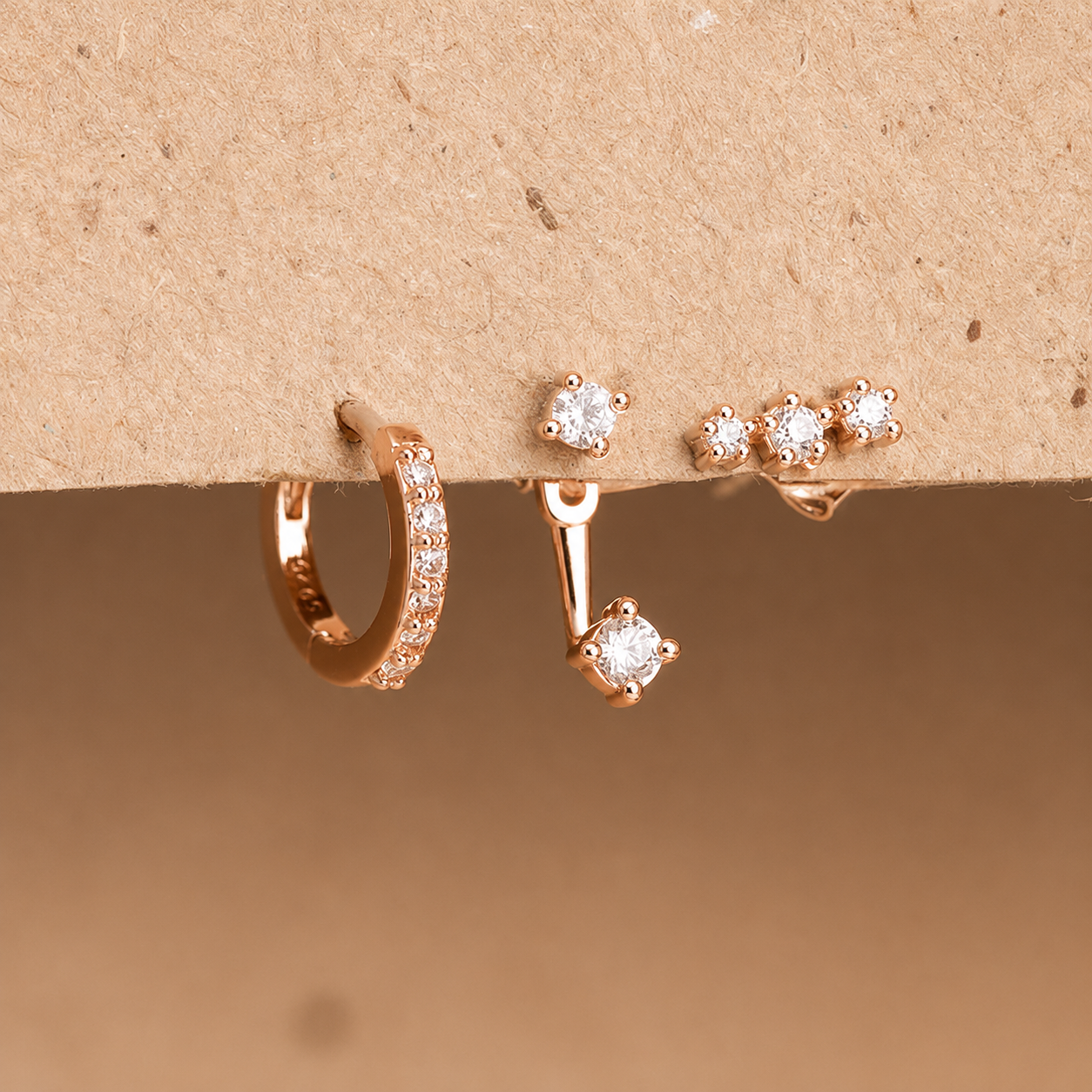 Set of rose gold earrings on a beige background