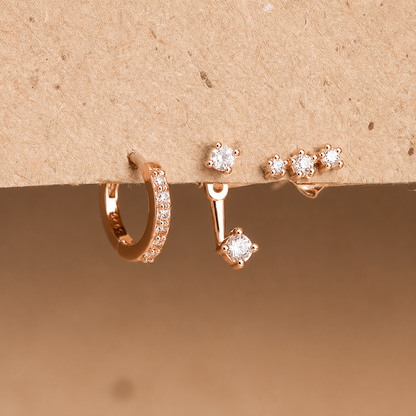 Set of rose gold earrings on a beige background