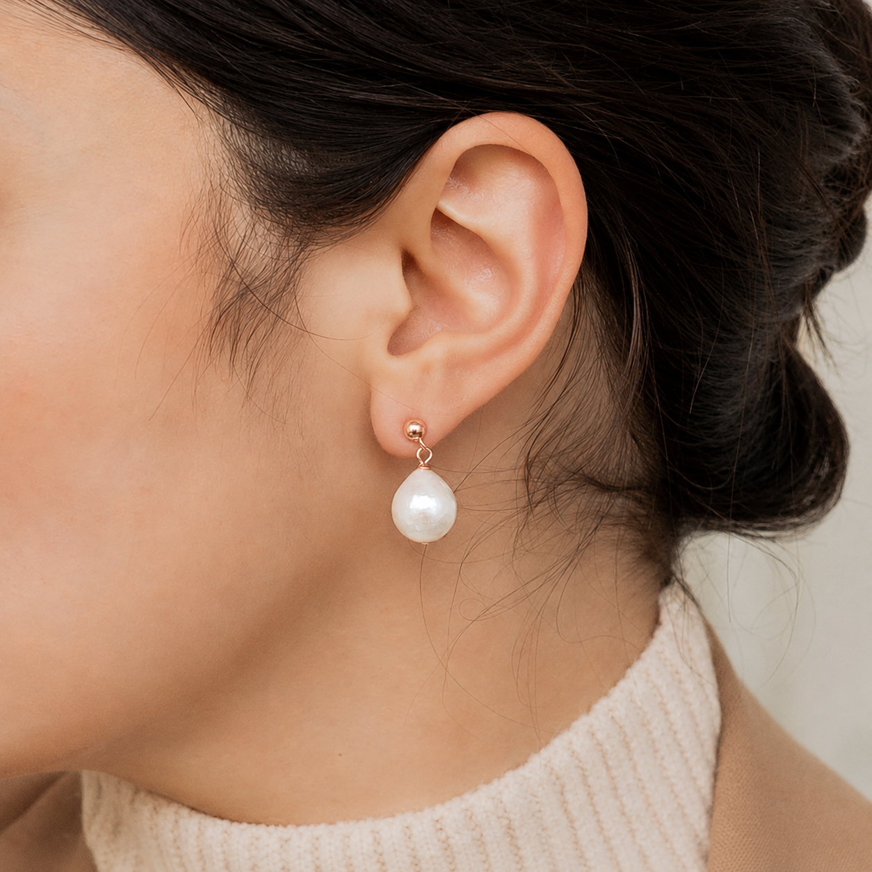 Pearl earring worn by a person with a neutral background