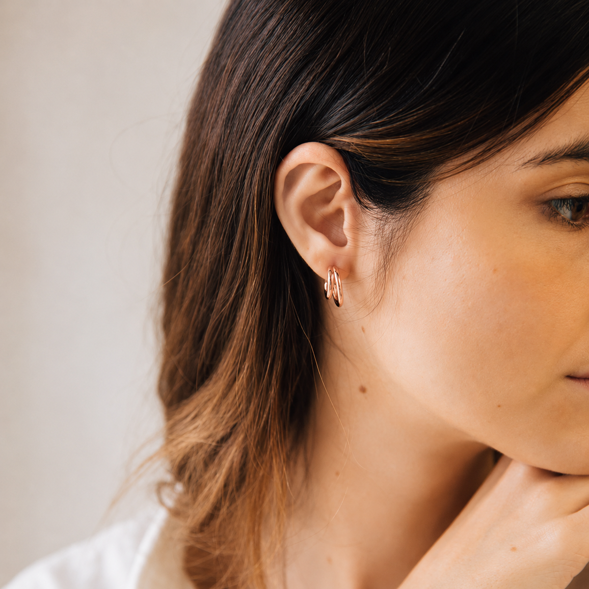 Close-up of a woman wearing a delicate earring with a neutral background