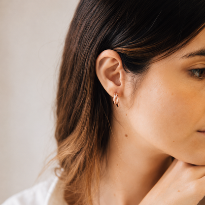 Close-up of a woman wearing a delicate earring with a neutral background