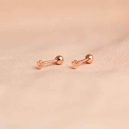 Rose gold bar-shaped earrings on a beige fabric background