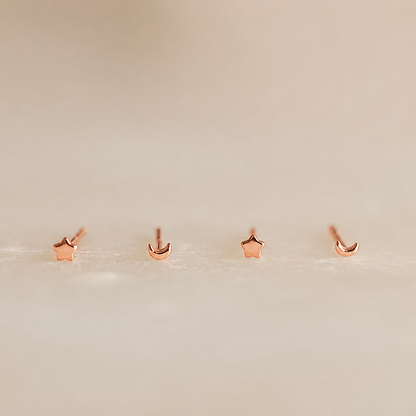 Set of rose gold star and moon earrings on a light beige background