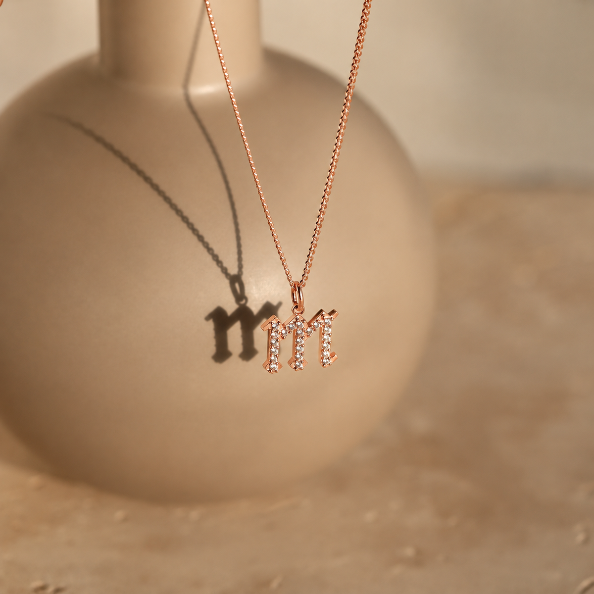 Rose gold necklace with 'MI' pendant on a beige background
