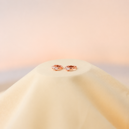 Rose gold earrings on a soft beige background