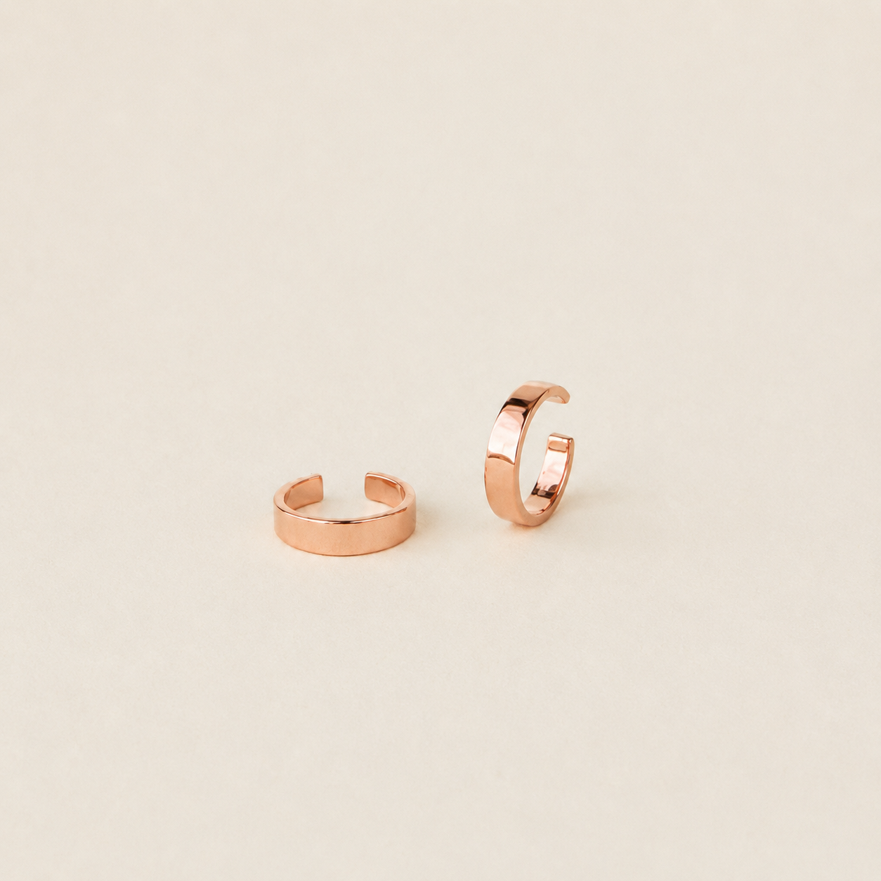 Rose gold hoop earrings on a beige background