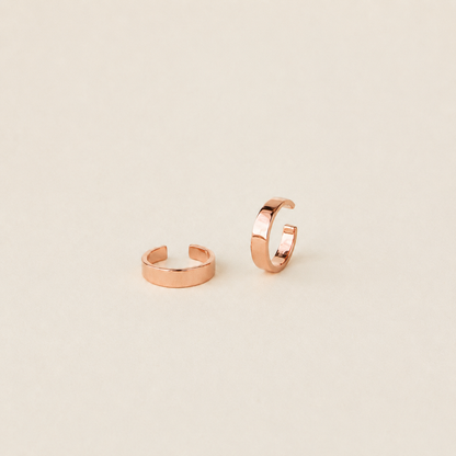 Rose gold hoop earrings on a beige background