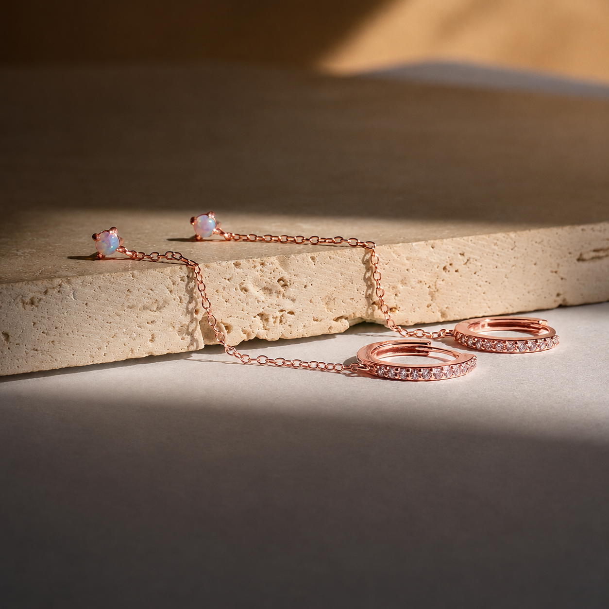Rose gold jewelry set on a textured surface with warm lighting