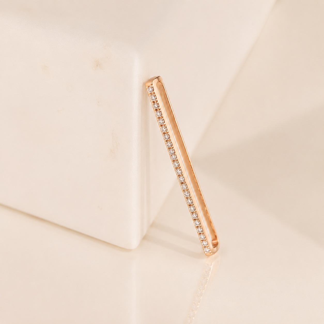 Rose gold ring with embedded diamonds on a beige background