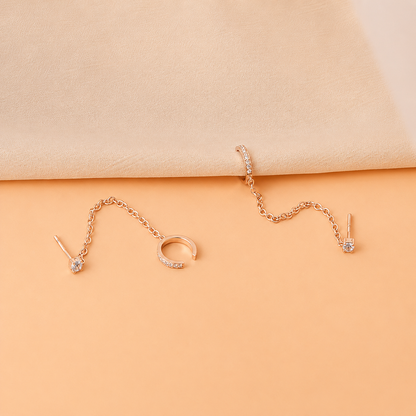 Rose gold jewelry set including earrings and a ring on a beige background