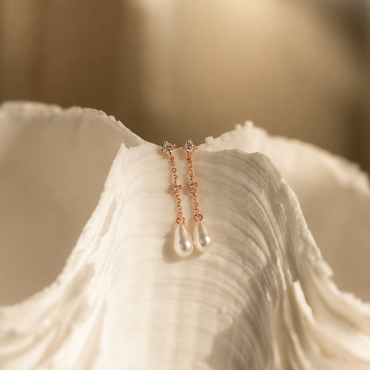 Rose gold earrings with pearl drops on a white shell
