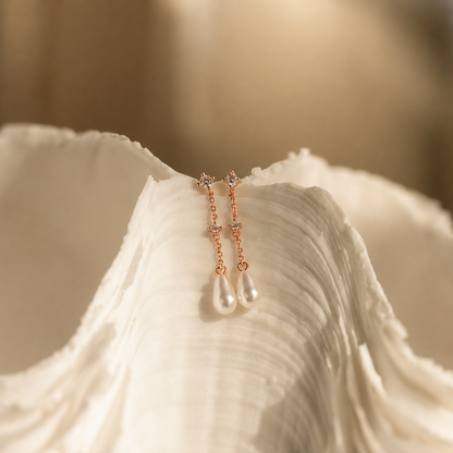 Rose gold earrings with pearl drops on a white shell