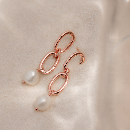 Rose gold earrings with pearls on a beige background