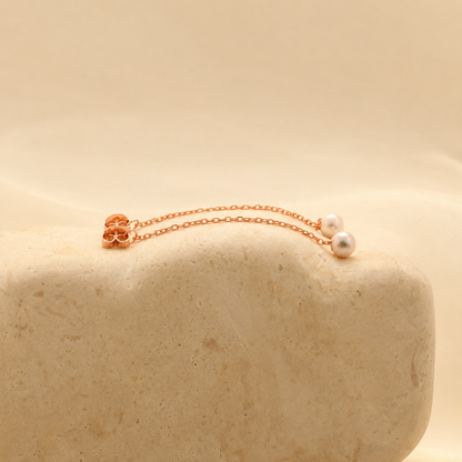 Rose gold bracelet with pearls on a beige stone surface