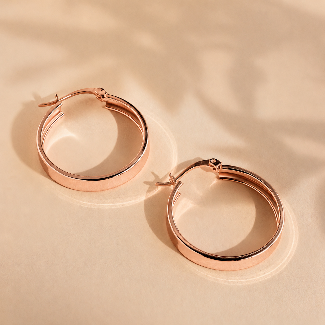 Rose gold hoop earrings on a beige background