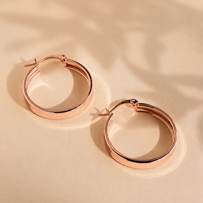 Rose gold hoop earrings on a beige background