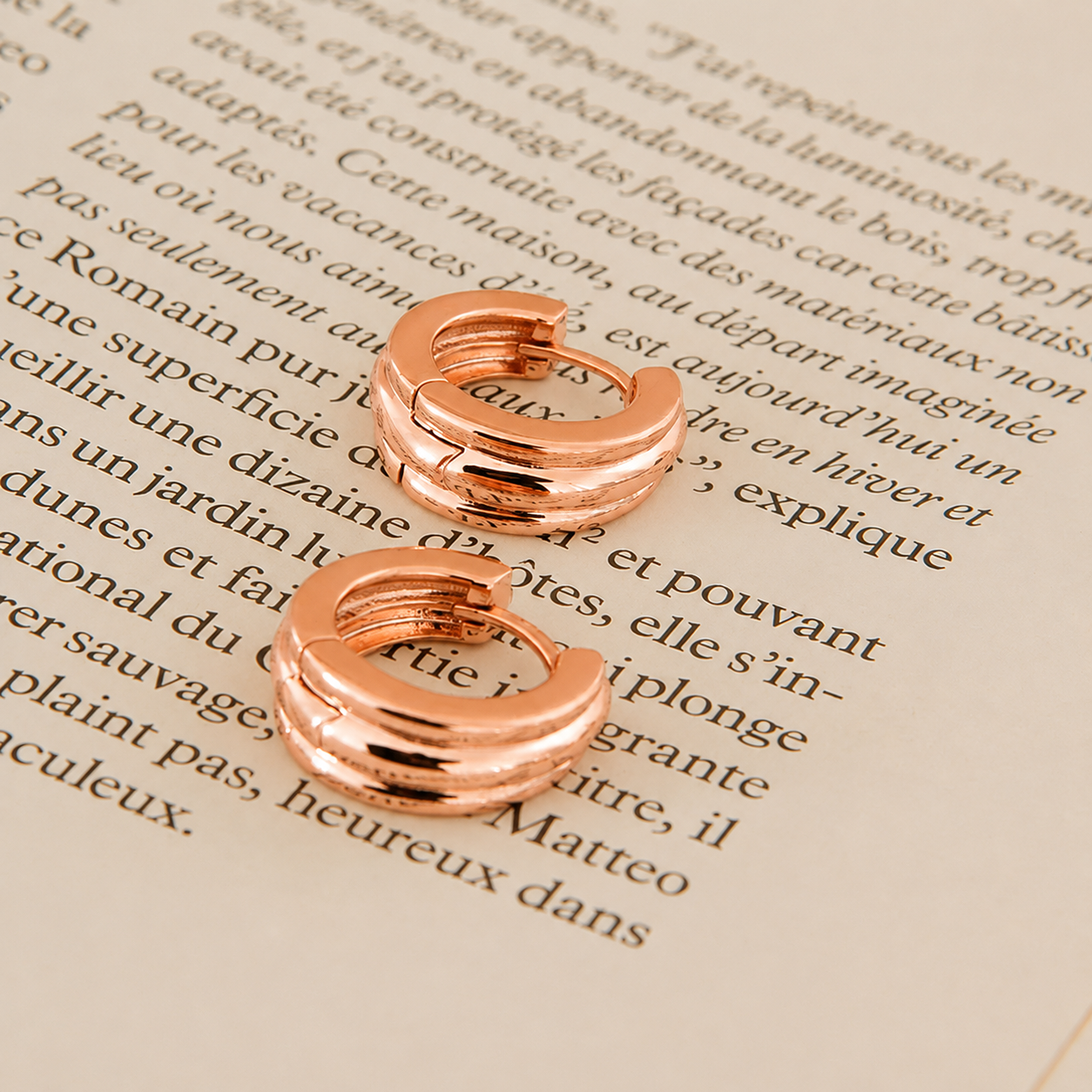 Rose gold hoop earrings on a piece of text