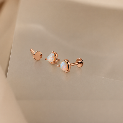 Rose gold earrings with heart-shaped gemstones on a beige background