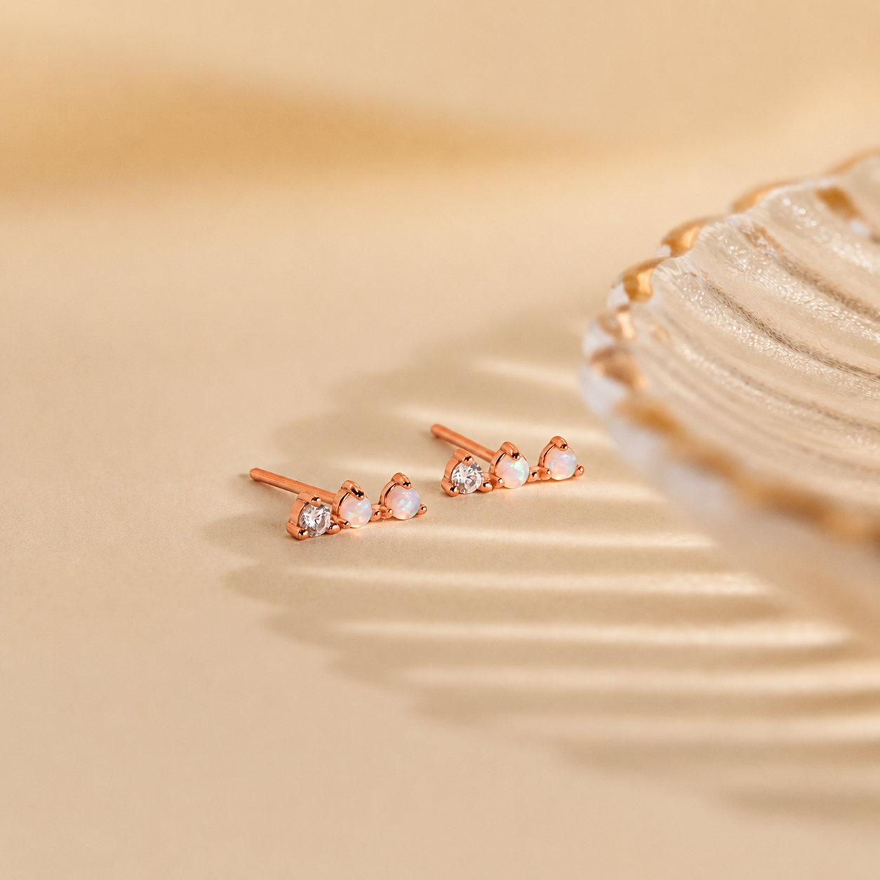 Rose gold earrings with clear stones on a beige background