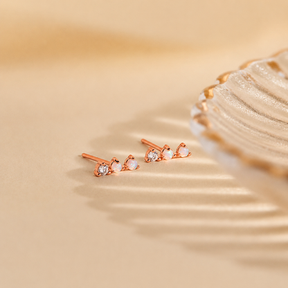 Rose gold earrings with clear stones on a beige background