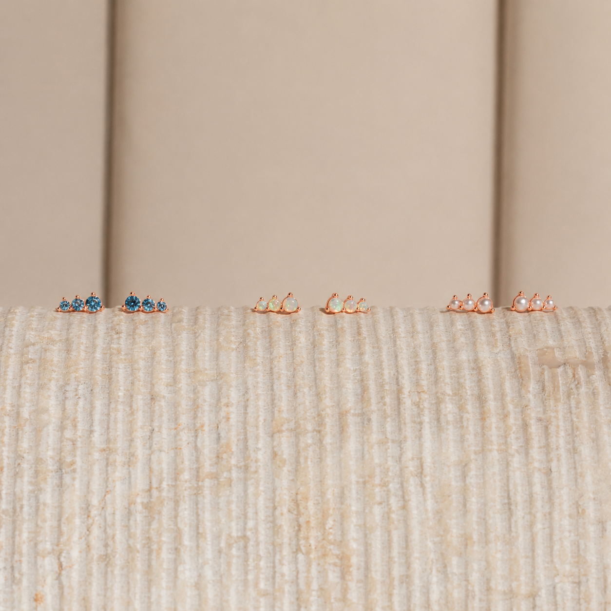 Set of small earrings on a textured surface with a neutral background