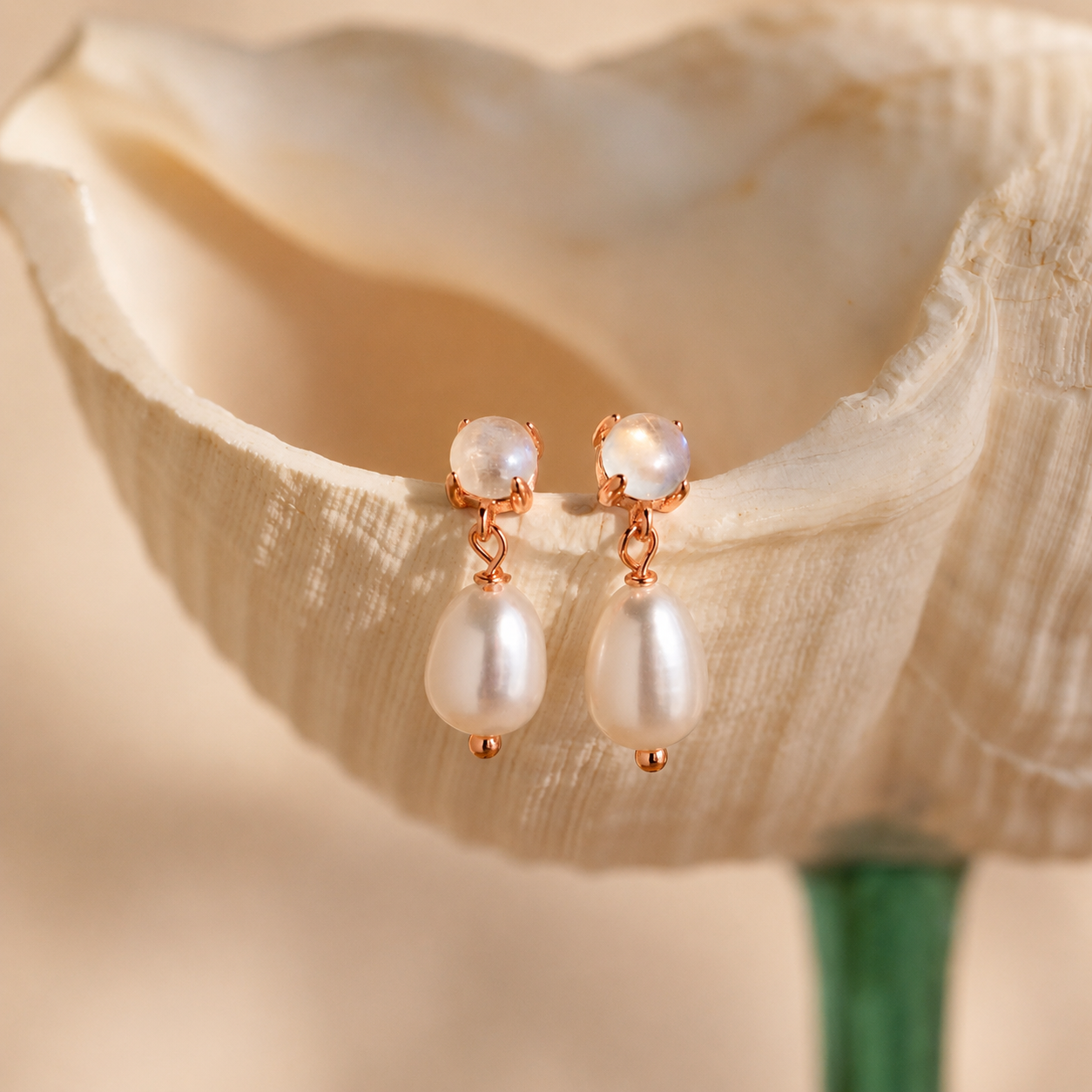 Pearl earrings with rose gold accents on a light beige background