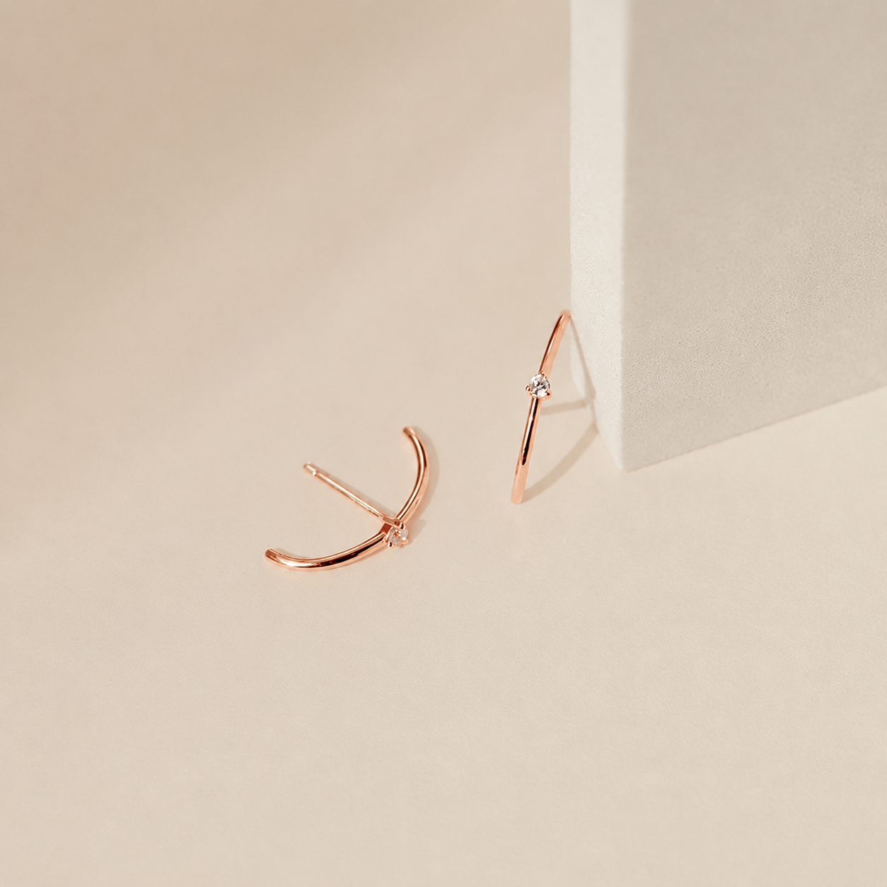 Rose gold earrings on a beige background