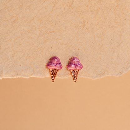 Pair of pink ice cream cone earrings on a beige background