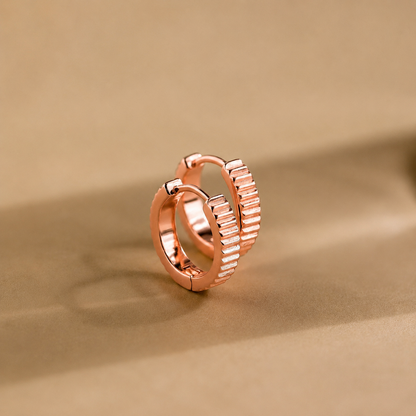 Rose gold hoop earring on a beige background