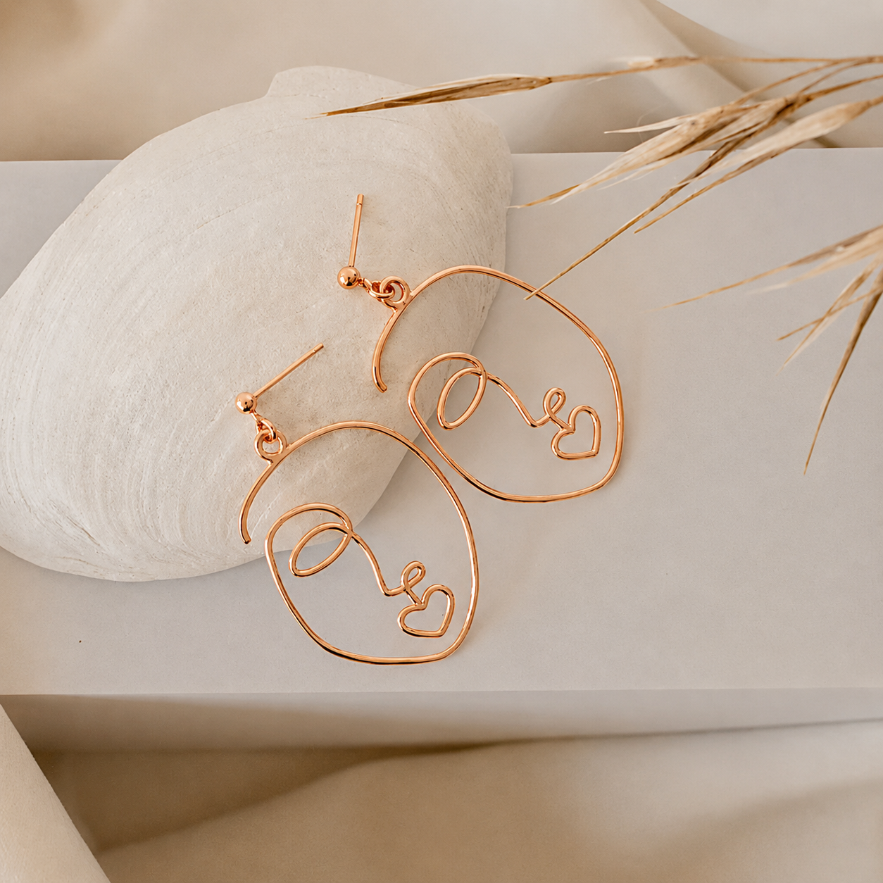 Rose gold hoop earrings on a neutral background with decorative elements