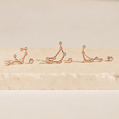 Rose gold constellation earrings on a beige background