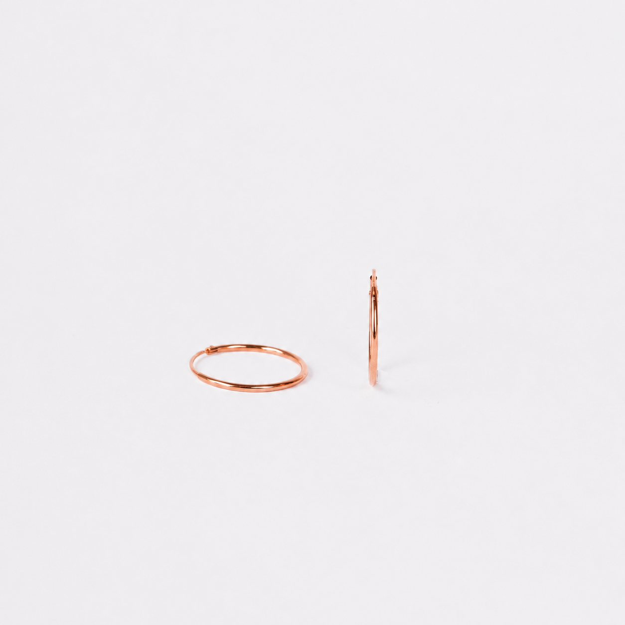 Rose gold hoop earrings on a light gray background