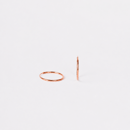 Rose gold hoop earrings on a light gray background
