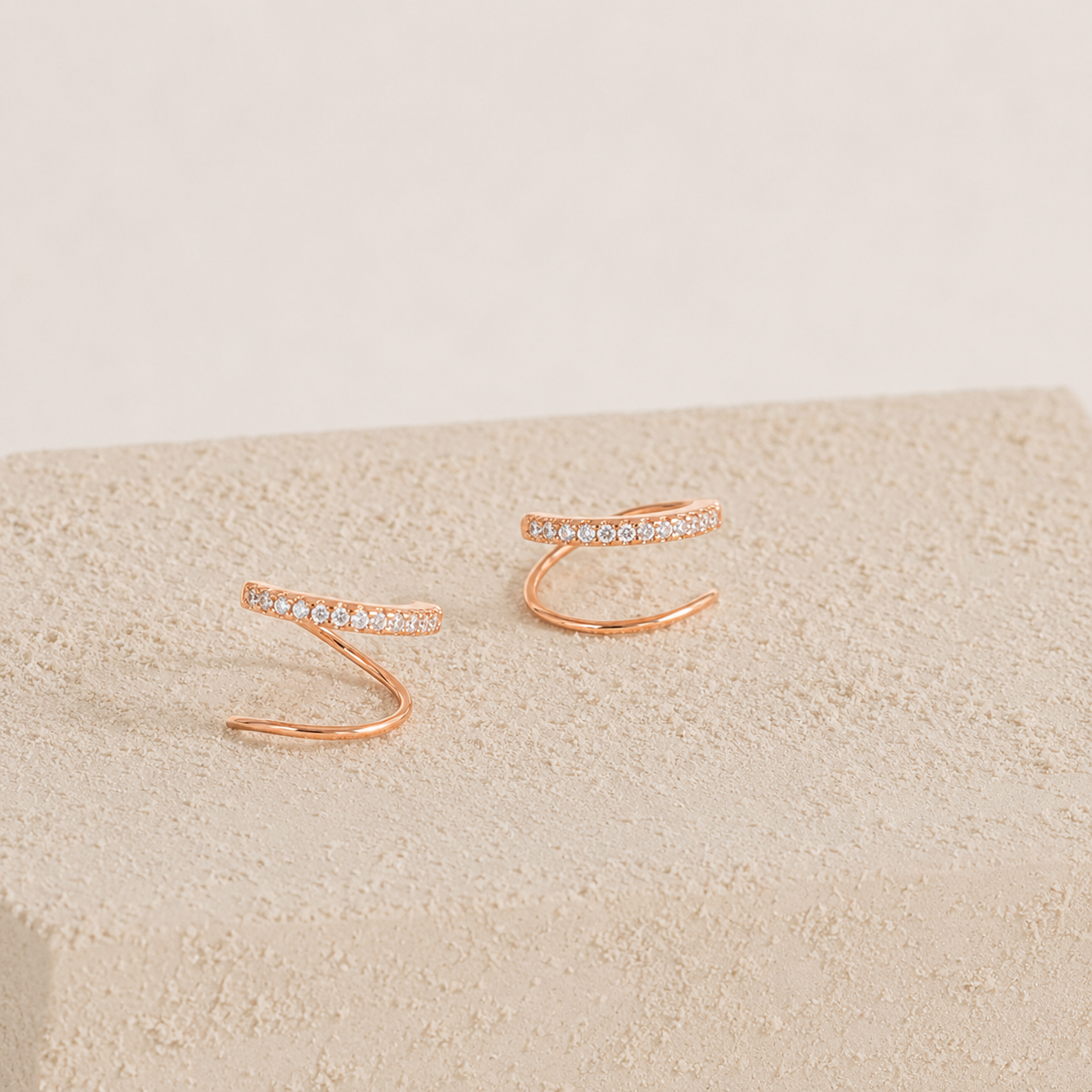Rose gold open rings with small stones on a beige fabric background