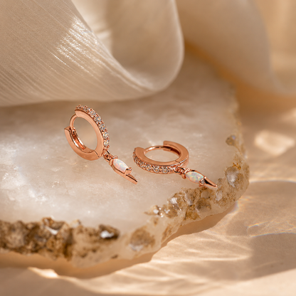 Rose gold jewelry set with gemstones on a textured beige surface
