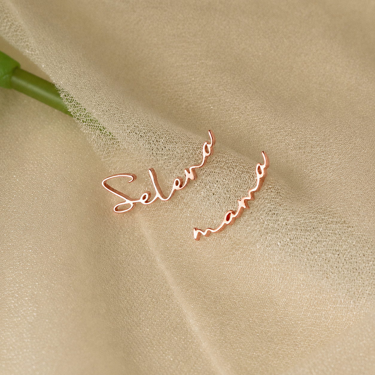 Rose gold 'Selena' earrings on a beige fabric background