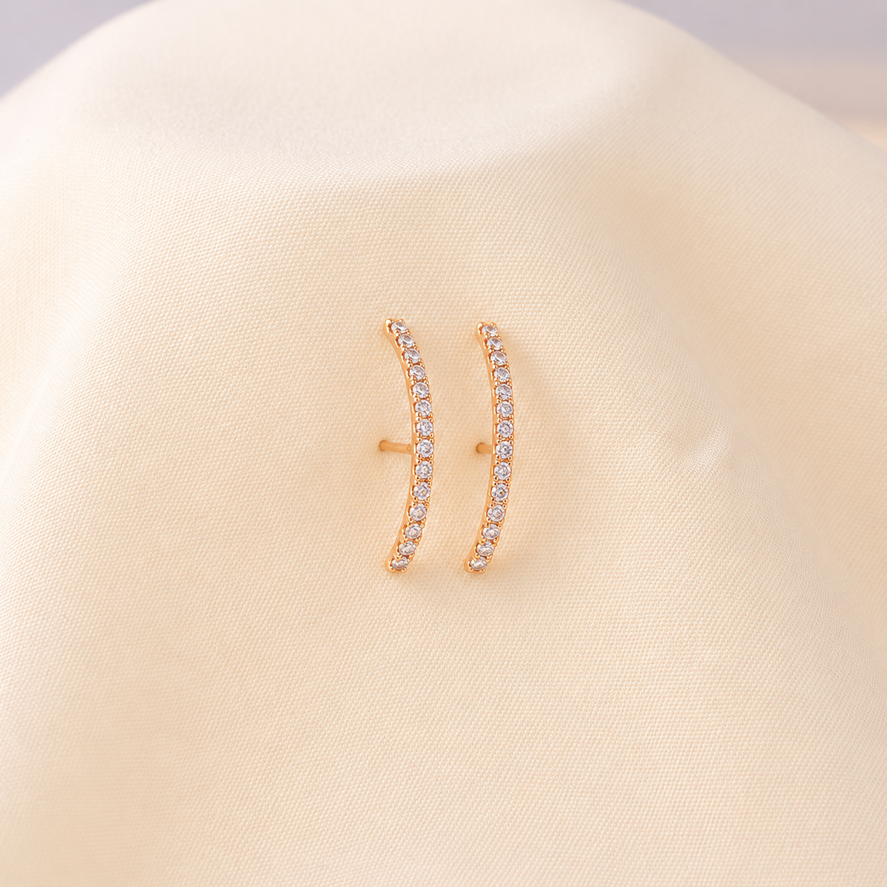 Gold earrings with small diamonds on a beige background