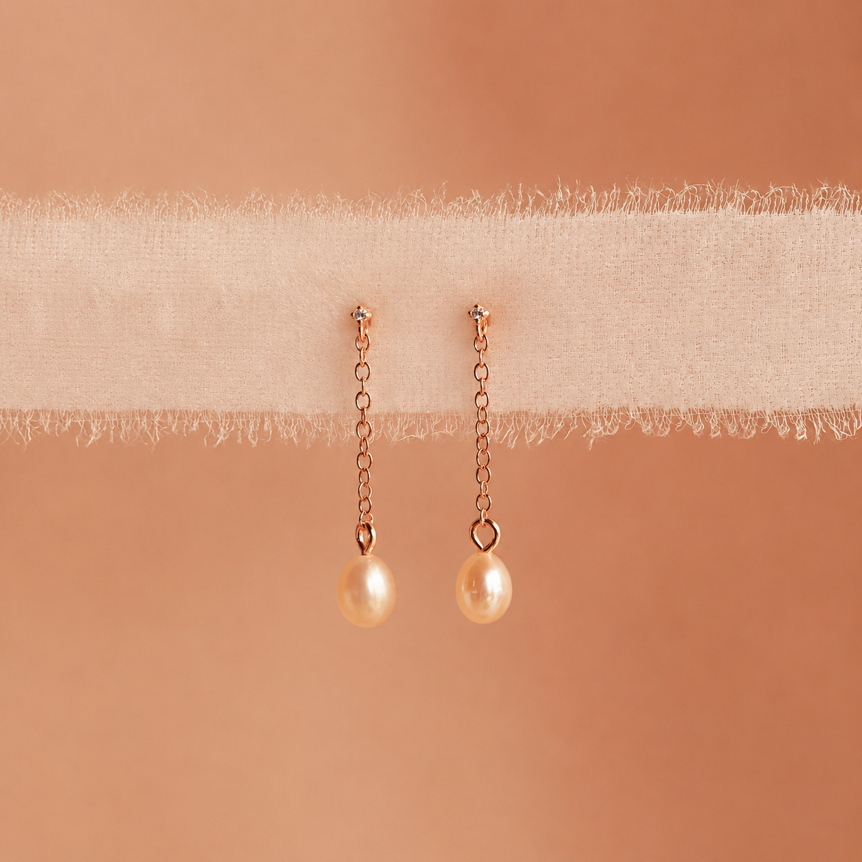Pair of pearl earrings on a beige fabric background