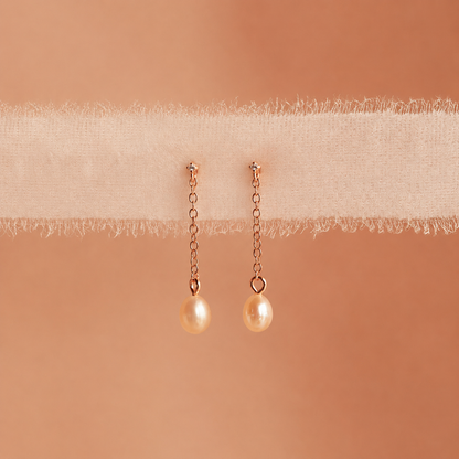 Pair of pearl earrings on a beige fabric background