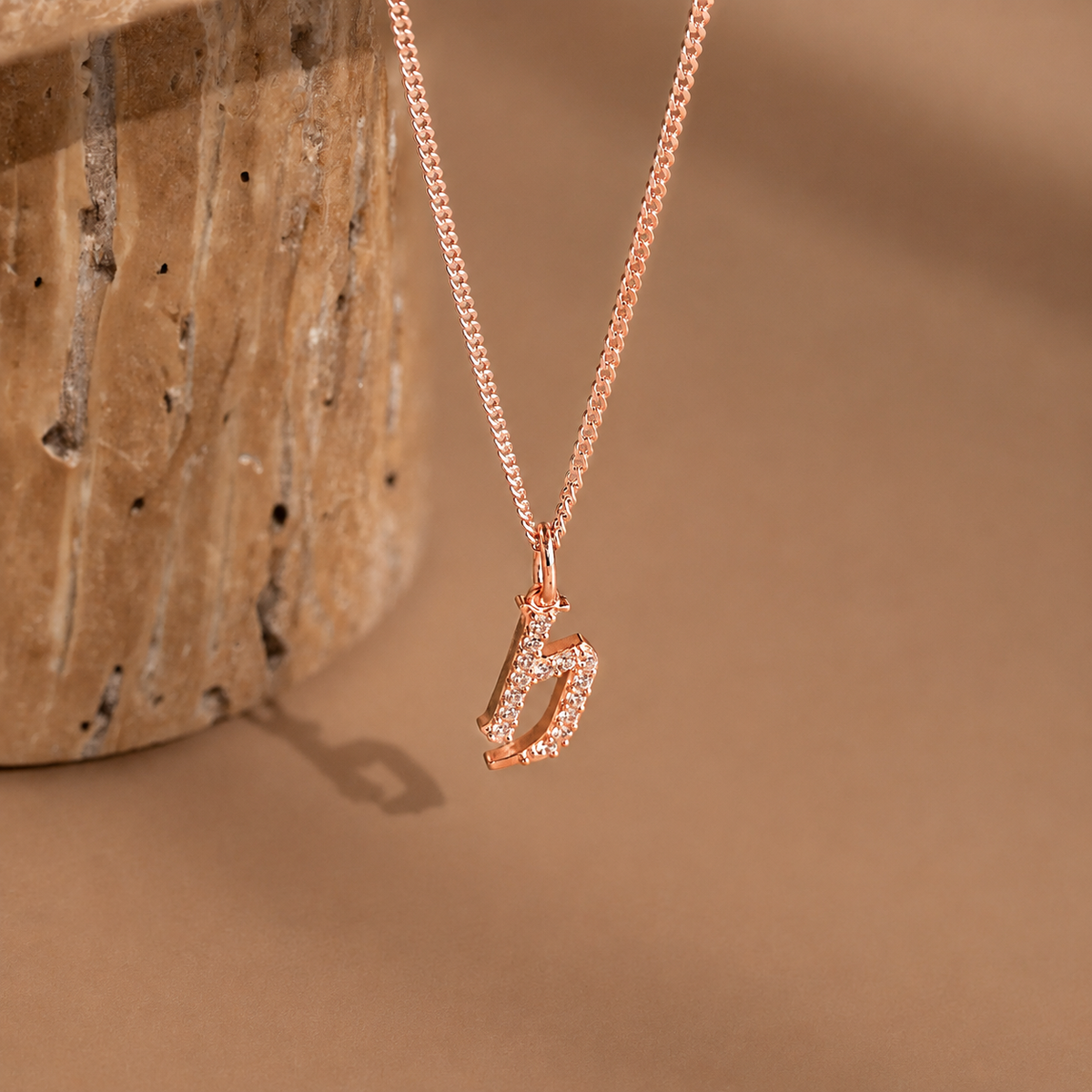 Rose gold necklace with a unique pendant on a beige background